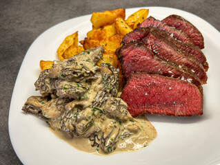 Juicy steak served with potatoes and morel creamy sauce