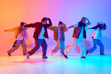 Dynamic performance of five talented dancers in motion, dancing modern dance against gradient studio background in neon light. Concept of modern dance style, hobby, active lifestyle, youth culture