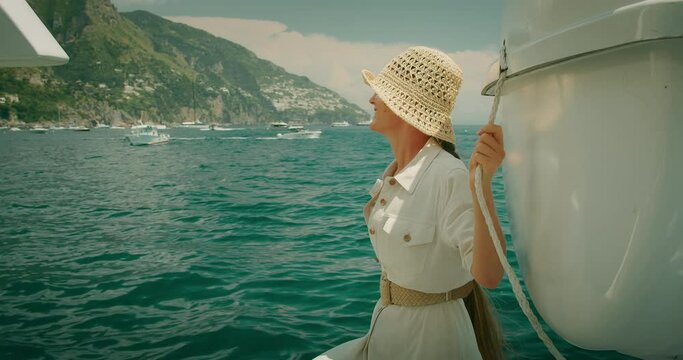 Traveler reaching out to the Mediterranean sea on the boat. Joyful woman enjoying light breeze on summer sunny day. Trip to the Capri Island, Italy.