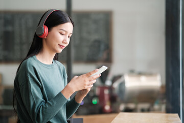 A woman wearing headphones is looking at her phone
