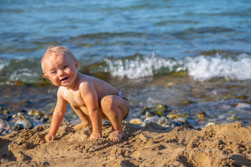 Fototapeta na wymiar Little baby having fun outdoors at the seaside. Summer holiday, rest, vacation, people, joy, happiness concept. Copy space for text or design.