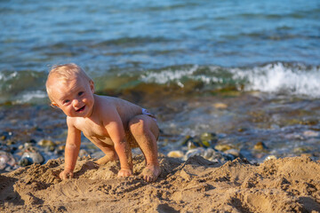 Funny portrait of little baby having fun outdoors at the seaside. Summer holiday, rest, vacation, people, joy, happiness concept. Copy space for text or design.
