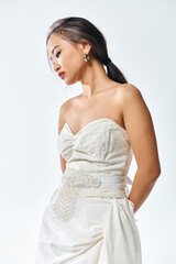 graceful asian young woman in white dress with red lips and pearl necklace posing