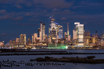 New York City skyline with illuminated Hudson Yards skyscrapers in evening. Manhattan Midtown West cityscape view from across the Hudson River