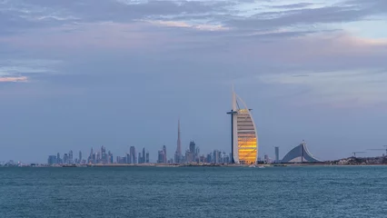 Fotobehang Dubai skyline with Burj Al Arab hotel during sunset and day to night timelapse. © neiezhmakov