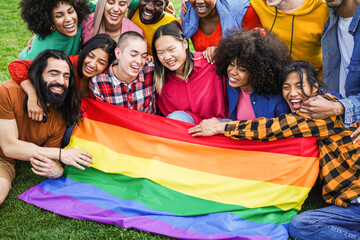 Diverse people having fun holding LGBT rainbow flag outdoor - Multiracial friends having fun...