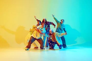Photo sur Aluminium École de danse Diverse people, dancers in colorful casual clothes, standing in dynamic jumping pose, performing over gradient green yellow background in neon. Concept of modern dance style, active lifestyle, youth
