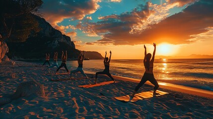 The image shows a group of people doing yoga on the beach at sunset. The sun is setting over the...