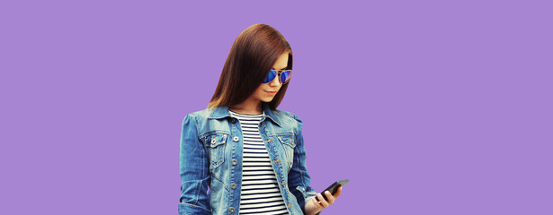 Modern young woman with mobile phone on purple studio background