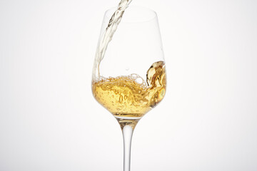 Stream of white wine flows into stem glass, swirls. - 767107649