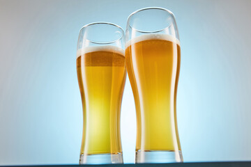 Yellow alcoholic fizzy drink, brew fills glasses to brim.