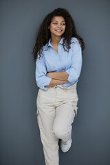 Smiling attractive young business woman in blue shirt posing on gray background