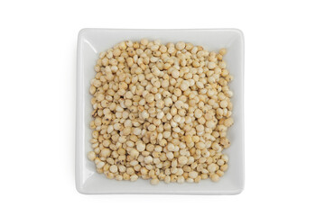 Sorghum seeds in ceramic bowl isolated on white background. Top view. Flat lay.