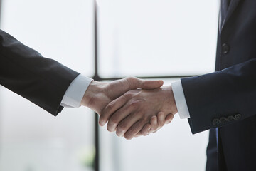 Close up of handshake on blurry conference room interior background. Partnership concept