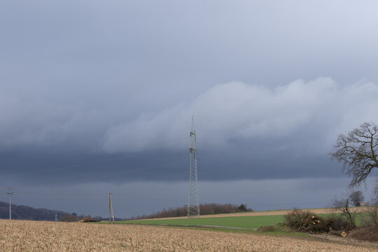Holz am Waldrand gesammelt vorbereitet gelagert zum Schreddern f&uuml;r Holzh&auml;cksel im Kalletal an einem Tag mit Regen Sturm Wolken auf der Steinegge im Hintergrund Stromleitung und Strommasten