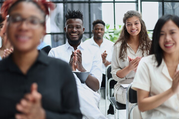 businesswoman applauding during seminar near interracial colleagues - obrazy, fototapety, plakaty