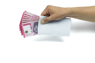 Asian man's hand holding white envelope containing stack of IDR 100,000 cash. Indonesian rupiah...