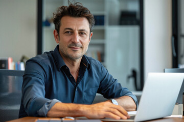 Fototapeta premium Middle aged business man executive financial investor sitting at desk using laptop. Busy professional businessman ceo manager working on computer corporate technology in modern office. Portrait.