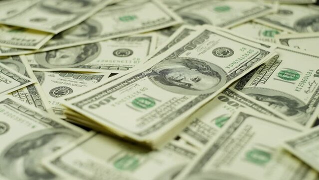 A woman's hand counts money on a separate stack on the table. A lot of cash dollar bills are laid out on the surface. High quality 4k footage
