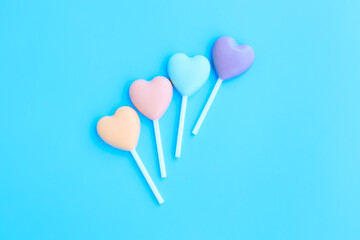 Multicolored heart shaped lollipop on blue background, Chocolate candy