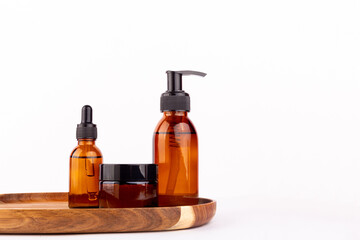 Brown glass jar for natural cosmetics on wooden stand isolated on white background. Buying goods without plastic packaging. Zero waste and sustainable plastic free lifestyle. Front view..