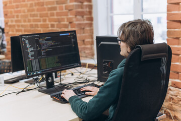software developer young long-haired man working with computer in office