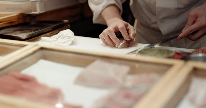Cooking, hands and sushi chef knife in a restaurant with catering, fish chop and Japanese dish in kitchen. Menu, culinary artist and fine dining with tuna and person with food and sashimi for dinner