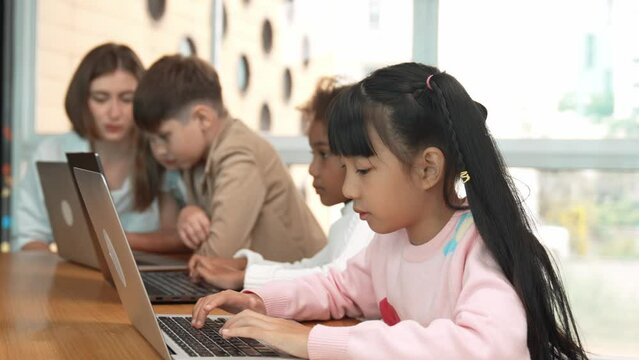 Group of multiethnic children working or playing laptop, programing system. Happy funny diverse student working by using laptop to writing prompt or programing system. Smart classroom. Erudition.