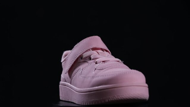 Pink sport shoe spinning on black background. Running shoe, sneaker or trainer. Cute girl's shoe. Fitness, sport, training concept.