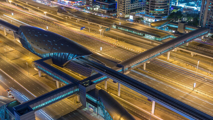 Futuristic building of Dubai metro and tram station and luxury skyscrapers behind night timelapse