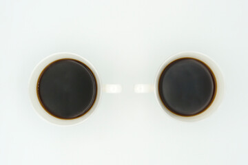 black coffee poured into a two porcelain coffee cup on a black background