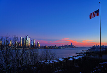 WEEHAWKEN, NJ -18 FEB 2024- Sunset view of the waterfront skyline in Manhattan, New York, seen from across the Hudson River in New Jersey. - obrazy, fototapety, plakaty
