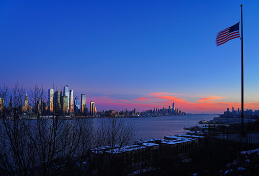 Fototapeta WEEHAWKEN, NJ -18 FEB 2024- Sunset view of the waterfront skyline in Manhattan, New York, seen from across the Hudson River in New Jersey.