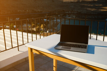 Laptop on the table on the balcony. Freelancing and remote work concept. - 767149693