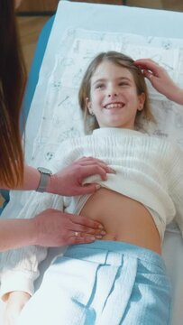 Vertical shot of a A female doctor examines the patient's stomach, conducting a clinical examination of the body little girl	