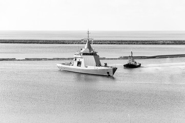 Coast Guard Ship entering port with the help of a tugboat, after exercises at sea.