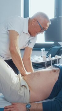 Vertical shot of a eelderly urologist doctor performs a medical examination on a middle-aged male patient in a private clinic