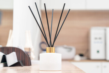 Aroma diffuser for perfumed liquid and reed sticks in the room on a wooden table