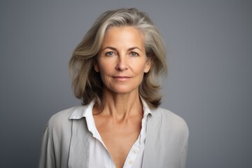 Portrait of mature businesswoman with grey hair against grey background.