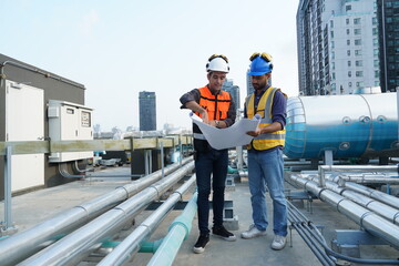 Foreman engineer and contractor wearing reflective jacket, engineering helmet, holding blueprints...