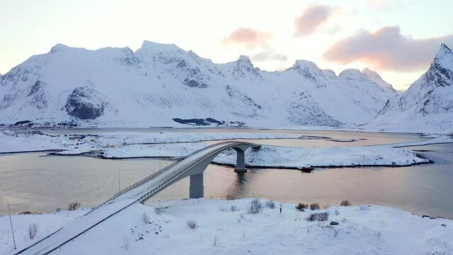 4k drone flight moving to the side footage (Ultra High Definition) of Lofoten Islands. Exotic winter sunrise on Norway. Frosty morning view of Fredvang bridge with Volandstind peak on background.