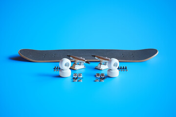 Disassembled Black Skateboard and Components on Bright Blue Surface