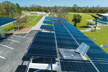 Hurricane wind damage to solar panels installed as shade roof over parking lot for parked electric...