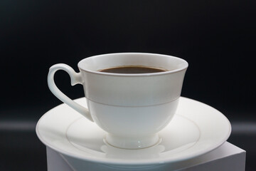 black coffee poured into a porcelain coffee pair on a black background