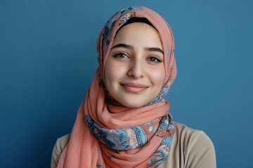 Portrait of smiling woman in hijab on blue background