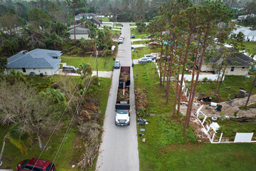 Aerial view of Hurricane Ian special aftermath recovery dump truck picking up vegetation debris from Florida suburban streets. Dealing with consequences of natural disaster © bilanol