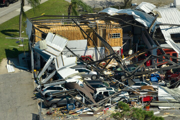 Destroyed by hurricane industrial building with damaged cars under ruins in Florida. Natural...