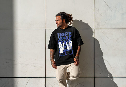 Mockup of man by wall wearing customized t-shirt