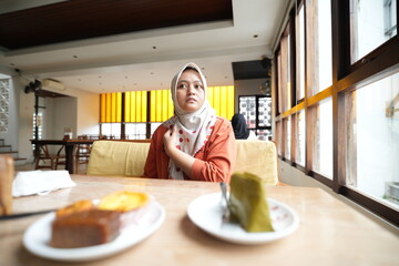 A woman wearing a hijab is in a cafe