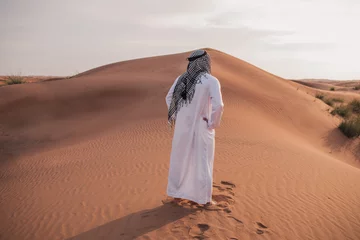 Poster Arab man stands alone in the desert and watching the sunset. © _chupacabra_